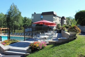 A poolside area with outdoor seating and a building in the background. - 3BR Near Golf - Balcony - Pool - Tennis Courts (Laconia)
