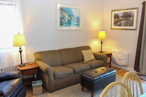 A living room with a sofa, two lamps, a framed painting, and a small table. - 3BR Near Golf - Balcony - Pool - Tennis Courts (Laconia)