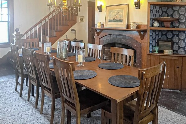 A dining area with a wooden table and chairs, a fireplace, and a staircase.