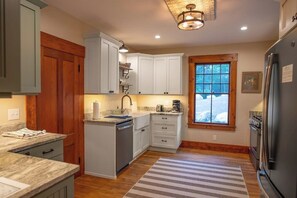A kitchen with white cabinets, a built-in dishwasher, and a refrigerator.