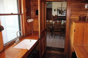 A wooden interior with a sink, chairs, and a dining table.