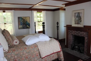 Une chambre à coucher avec un lit, une cheminée et des œuvres d’art accrochées aux murs.