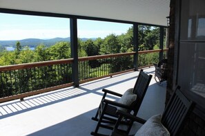 Un balcon avec vue sur un lac et des montagnes, une balustrade en bois et une chaise.