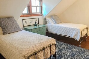 A bedroom with two beds, a nightstand, and a window.