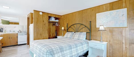 Un dormitorio con cama, mesitas de noche, armario y una zona de cocina.
