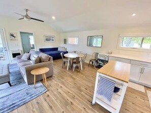 A modern living space with a sofa, dining table, chairs, and a kitchen area. - 4BR lakefront home - dock, boat slip, & game room (Alton)