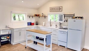 A modern kitchen with white cabinetry, a wooden countertop, a gas stove, and a refrigerator. - 4BR lakefront home - dock, boat slip, & game room (Alton)