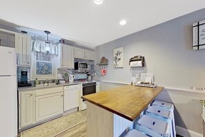 A modern kitchen with white cabinetry, a wooden island, and a microwave.