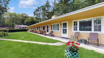 Un motel avec une rangée de chambres, une pelouse bien entretenue et un parterre de fleurs.
