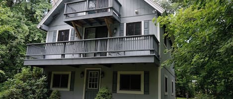 Ein zweistöckiges Haus mit einem Balkon, umgeben von viel Grün.