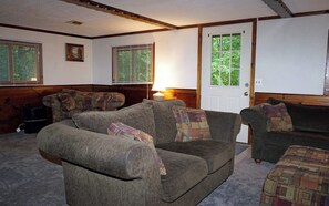 A cozy living room with two sofas, a lamp, and a door leading to a green outdoor area.