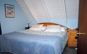 A bedroom with a bed, a nightstand, a lamp, and a door.