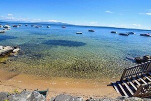 A clear beach with boats, a wooden staircase, and a rocky shoreline. - Lake-view 2BR with lakefront swimming, pools (Gilford)