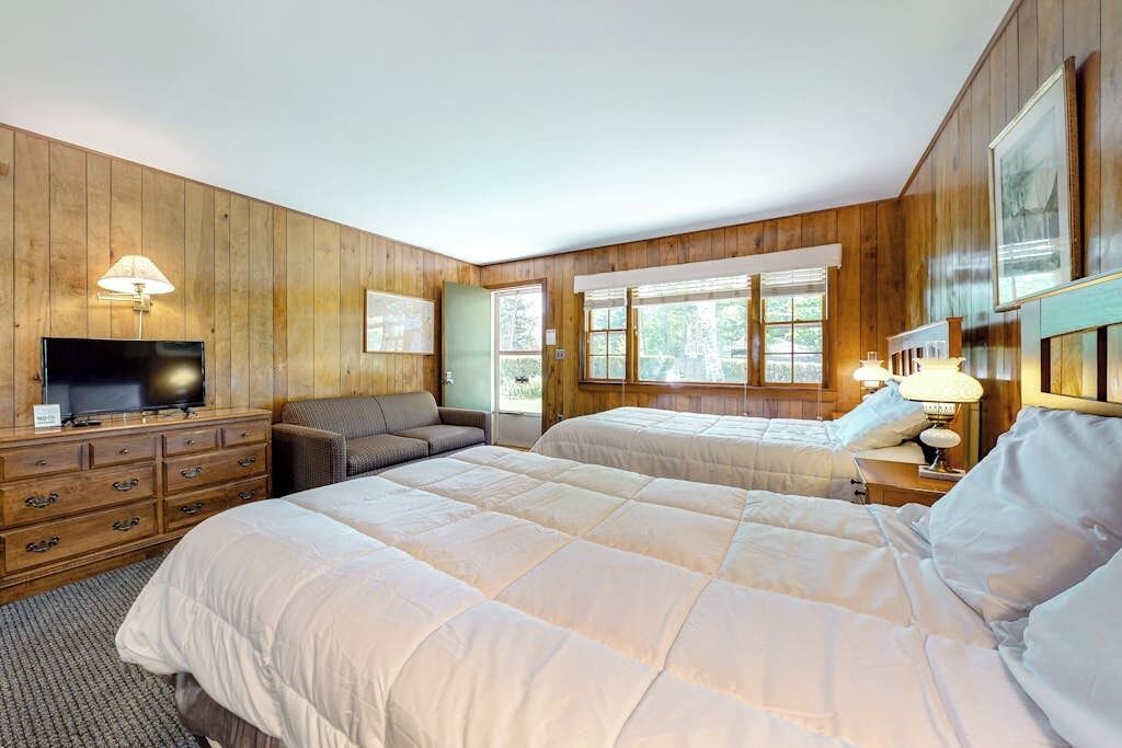 Une chambre avec deux lits, une télévision, un canapé et un lambris en bois.
