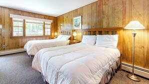 Ein Zimmer mit zwei Betten, Holzwänden, einem Fenster und einer Stehlampe.