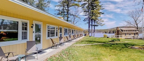 Une rangée de bâtiments jaunes à un seul étage, dotés de grandes fenêtres, de places assises en plein air et offrant une vue sur un lac.