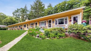 Ein gelbes Motel mit überdachter Veranda und angelegtem Garten.