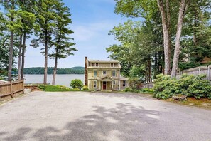 A two-story house with a front porch, surrounded by trees and a lake view. - Terrific Studio Lakefront - Kitchenette- Dock (Alton)