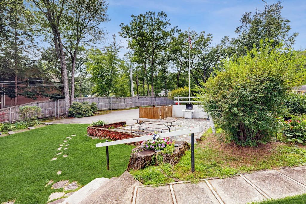 Un patio trasero con una mesa de picnic, una parrilla y una terraza de madera.
