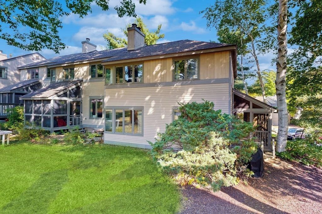 A two-story house with a covered porch, a visible deck, and a well-maintained lawn.