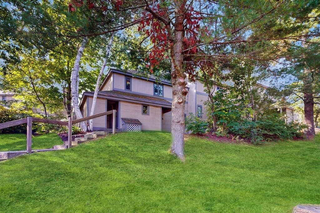 A two-story house with a front porch, a wooden fence, and a well-maintained lawn.