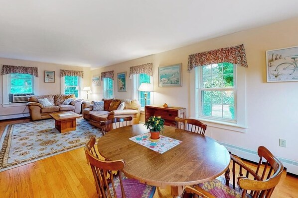 A living room with a round wooden table, a sofa set, and a dining area with chairs. - Updated 3BR Dog Friendly - Deck - Garage Parking (Gilford)
