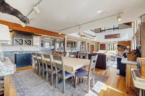 A spacious kitchen with a dining area, wooden beams, and a high ceiling.