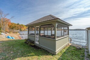 A small, single-story structure with a covered porch, situated by a body of water.