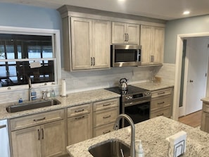A kitchen with light wood cabinets, stainless steel appliances, a granite countertop, and a window with a view. - 6BR lakefront with deck, dock, lawn & encl porch (Alton)