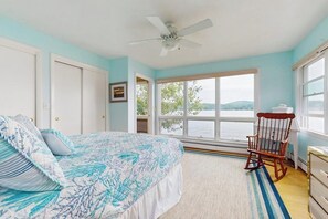 A bedroom with a bed, a rocking chair, a window with a view, and a ceiling fan. - 6BR lakefront with deck, dock, lawn & encl porch (Alton)