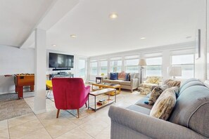 Een ruime woonkamer met een bank, fauteuils, een salontafel en een televisie.