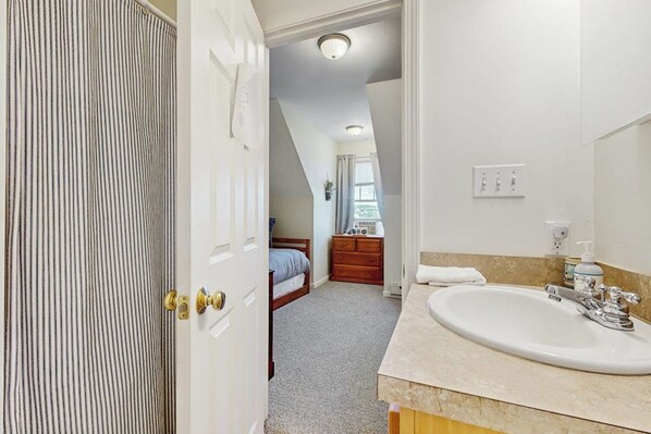 A bedroom with a bed, a dresser, and a bathroom with a sink and mirror. - Scenic 2BR Lakefront - Washer Dryer (Meredith)