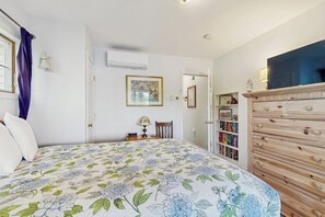 A bedroom with a bed, a dresser, a bookshelf, and a door leading to another room. - Scenic 2BR Lakefront - Washer Dryer (Meredith)
