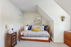 A bedroom with a bed, a dresser, a nightstand, a wall-mounted plant, and a ceiling with a sloped design. - Scenic 2BR Lakefront - Washer Dryer (Meredith)