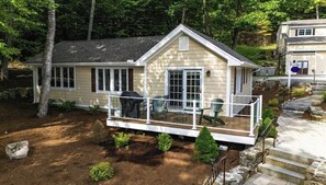 Ein Bungalow mit einer überdachten Veranda, einem Grill und einer kleinen Terrasse.