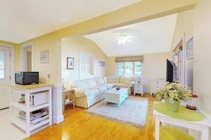A living room with a sofa, a coffee table, a TV, and a bookshelf. - Stunning 1BR Lakefront - Dock - Deck (Moultonborough)
