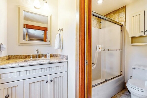 Ein Badezimmer mit Dusche, Toilette und Waschtisch mit Spiegel und Waschbecken.