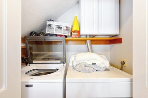 A laundry area with a washing machine, dryer, and a shelf with cleaning supplies. - 3BR Samoset Lakefront Townhouse (Gilford)