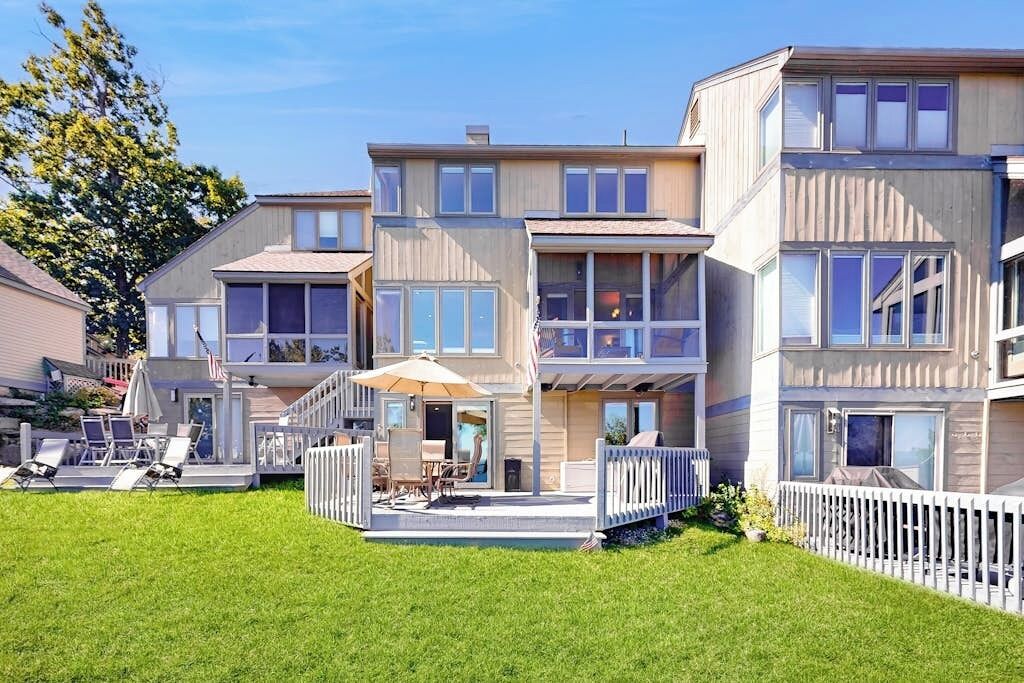 Een meerlaags woongebouw met een overdekte patio, buiten zitplaatsen en een witte picket fence.