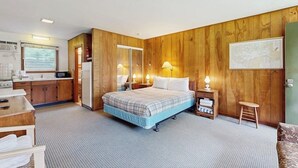 Ein Schlafzimmer mit einem Bett, Nachttischen, einem Schreibtisch und einer Küchenzeile.
