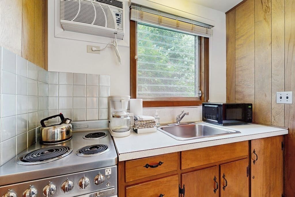 Une cuisine équipée d’une cuisinière, d’un four à micro-ondes, d’un évier et de meubles de rangement en bois.