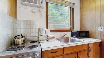 Une cuisine équipée d’une cuisinière, d’un four à micro-ondes, d’un évier et de meubles de rangement en bois.