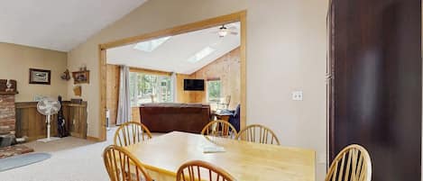 A dining area with a wooden table and chairs, a ceiling fan, and a view through an open doorway.