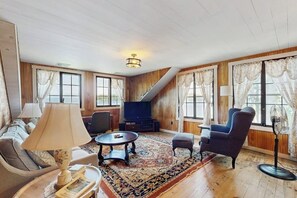A living room with a sofa, armchair, coffee table, and television. - Quintessential 4BR Lakefront-Dock (Meredith)