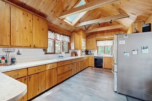 A kitchen with wooden cabinets, a stainless steel refrigerator, and a skylight. - Quintessential 4BR Lakefront-Dock (Meredith)