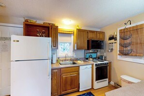 A compact kitchen with wooden cabinets, a white refrigerator, a stove, and a dishwasher. - Conveniently located 1BR 2nd-Floor - Deck (Gilford)