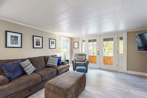 A living room with a brown sofa, a patterned armchair, and a television mounted on the wall.