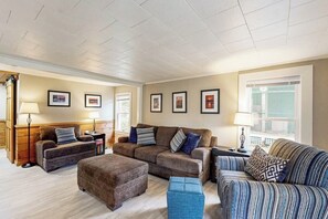 A living room with a sectional sofa, ottoman, and two side tables with lamps. - 4BR charming central cottage, walk to lake & town (Alton)