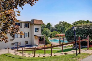 A residential building with a swimming pool, a covered patio, and a wooden fence. - Charming 2BR Lakeview 2nd-floor - Balcony - Pool (Laconia)