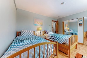 A bedroom with two beds, a nightstand, a lamp, a painting, and a mirror. - Charming 2BR Lakeview 2nd-floor - Balcony - Pool (Laconia)